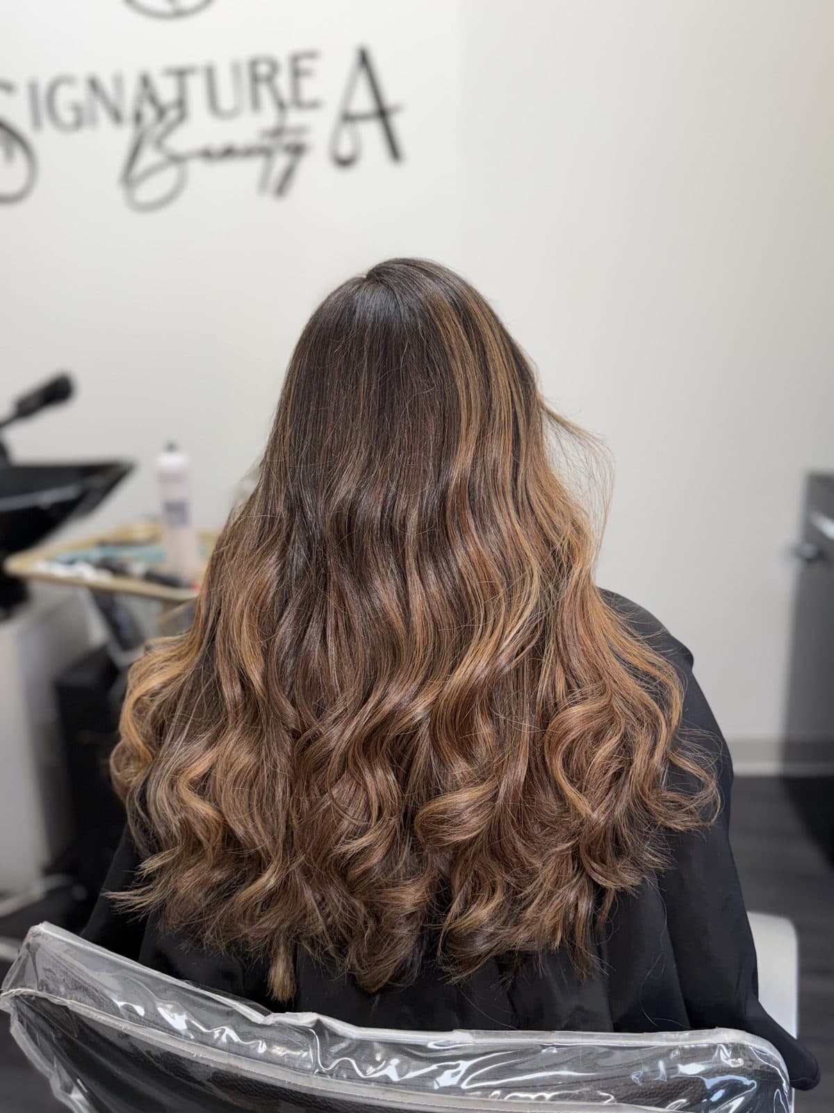 Balayage quente em cabelo castanho longo e ondulado, visto de costas